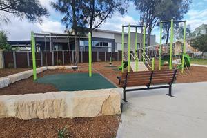 Photo of newly upgraded playground with swings, slide and bench seat